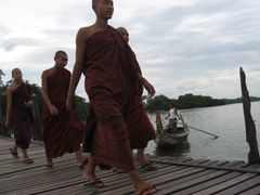 Buddhističtí mniši na mostě U Bein přes jezero Taungthamay nedaleko Mandalaje