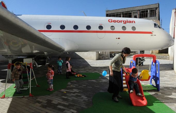 A picture taken on October 29, 2012, shows children playing near a Soviet-era Yakovlev Yak-42 plane turned into their kindergarten in the Georgian city of Rustavi, some 25 km southeast of the capital Tbilisi. Local head teacher Gari Chapidze bought the old but fully functional Yak-42 from Georgian Airways and refurbished its interior with educational equipment, games and toys but left the cockpit instruments intact so they could be used as play tools.