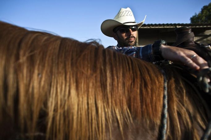 Alon, an Israeli cowboy, unloads his horse after working with cattle in the early morning, on a ranch just outside Moshav Yonatan, a collective farming community, about 2 km (1 mile) south of the ceasefire line between Israel and Syria in the Golan Heights May 21, 2013. Cowboys, who have been running the ranch on the Golan's volcanic rocky plateau for some 35 years, also host the Israeli military, who use half of the cattle farm, 20,000 dunams (5,000 acres), as a live-fire training zone. Israel captured the Golan Heights from Syria in the 1967 Middle East war and annexed the territory in 1981, a move not recognized internationally. Picture taken May 21, 2013. REUTERS/Nir Elias (ENVIRONMENT ANIMALS SOCIETY) ATTENTION EDITORS: PICTURE 18 OF 27 FOR PACKAGE 'COWBOYS OF THE GOLAN HEIGHTS' SEARCH 'COWBOY GOLAN' FOR ALL IMAGES Published: Kvě. 29, 2013, 10:07 dop.