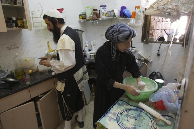 Rachel Kreus (R) kneads dough for traditional Jewish bread during her family's preparations for the Jewish Sabbath in Jerusalem's Mea Shearim neighbourhood June 29, 2012. The Kreus family are a member of Neturei Karta, a fringe ultra-Orthodox movement within the anti-Zionist bloc. The ultra-Orthodox Jews have gone from being a tiny minority in Israel's mostly secular society to its fastest-growing sector, now about 10 percent of the 7.8 million population. They are exempt from military duty in Israel but draft deferments and state subsidies for the ultra-Orthodox have become a divisive political issue in Israel, where the government must decide a new law by August to ensure more of them do military service. Picture taken June 29, 2012. REUTERS/Ronen Zvulun (JERUSALEM - Tags: RELIGION POLITICS FOOD MILITARY) ATTENTION EDITORS - PICTURE 18 OF 21 FOR PACKAGE "ISRAEL'S ULTRA-ORTHODOX". SEARCH "ULTRA-ORTHODOX" FOR ALL PICTURES Published: Čec. 6, 2012, 10:04 dop.