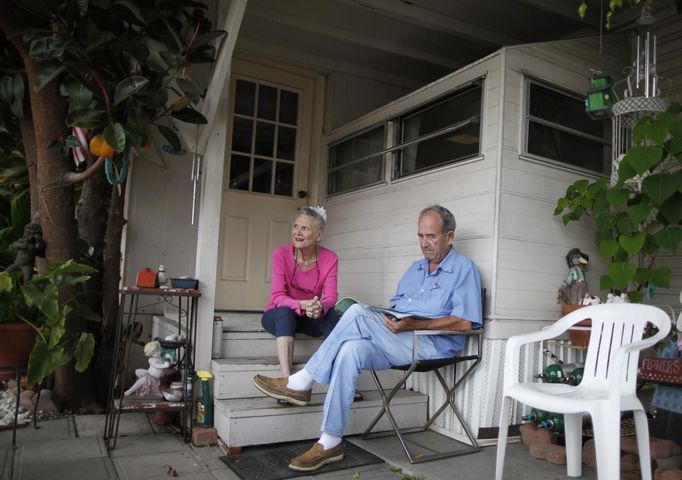 Paul Lewis (R), 82, and his wife Ruth, 84, sit outside their trailer in which they have lived for 15 years, in Village Trailer Park in Santa Monica, California, July 13, 2012. Developer Marc Luzzatto wants to relocate residents from the trailer park to make way for nearly 500 residences, office space, stores, cafes and yoga studios, close to where a light rail line is being built to connect downtown Los Angeles to the ocean. Village Trailer Park was built in 1951, and 90 percent of its residents are elderly, disabled or both, according to the Legal Aid Society. Many have lived there for decades in old trailers which they bought. The property is valued at as much as $30 million, according the LA Times. REUTERS/Lucy Nicholson (UNITED STATES - Tags: REAL ESTATE BUSINESS SOCIETY POLITICS) Published: Čec. 14, 2012, 7:54 dop.