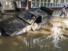 A local resident passes by a damaged car stuck in a flooded street in the town of Krymsk in Krasnodar region, southern Russia, July 8, 2012. Russian President Vladimir Putin ordered investigators to find out if enough was done to prevent 144 people being killed in floods in southern Russia after flying to the region to deal with the first big disaster of his new presidency. REUTERS/Eduard Korniyenko (RUSSIA - Tags: DISASTER ENVIRONMENT POLITICS TRANSPORT) Published: Čec. 8, 2012, 8 dop.