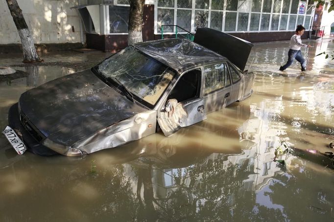 A local resident passes by a damaged car stuck in a flooded street in the town of Krymsk in Krasnodar region, southern Russia, July 8, 2012. Russian President Vladimir Putin ordered investigators to find out if enough was done to prevent 144 people being killed in floods in southern Russia after flying to the region to deal with the first big disaster of his new presidency. REUTERS/Eduard Korniyenko (RUSSIA - Tags: DISASTER ENVIRONMENT POLITICS TRANSPORT) Published: Čec. 8, 2012, 8 dop.