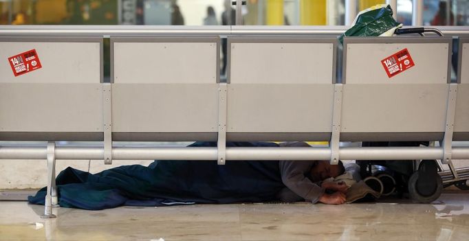 A man sleeps under a bench at Terminal 4 during a 24-hour nationwide general strike, at Madrid's Barajas airport November 14, 2012. Spanish and Portuguese workers are staging the first coordinated general strike across the Iberian Peninsula on Wednesday, shutting transport, grounding flights and closing schools to protest against spending cuts and tax hikes. REUTERS/Sergio Perez (SPAIN - Tags: POLITICS BUSINESS EMPLOYMENT CIVIL UNREST TRANSPORT) Published: Lis. 14, 2012, 9:09 dop.