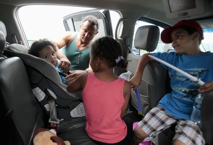 Jaden Fabian (L), 1, is strapped into her car seat by Estanislao Fabian as her family evacuates their home as Tropical Storm Isaac heads towards the Louisiana coast line in Oakville, Louisiana, August 28, 2012. Tropical Storm Isaac was near hurricane force as it bore down on the U.S. Gulf Coast on Tuesday and was expected to make landfall in the New Orleans area seven years after it was devastated by Hurricane Katrina. REUTERS/Sean Gardner (UNITED STATES - Tags: ENVIRONMENT DISASTER TRANSPORT) Published: Srp. 28, 2012, 2:02 odp.