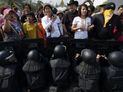 Protivládní demonstranti před policejním kordonem. Těžkooděnci chrání vládní budovu v thajské metropoli Bangkoku. (14. února 2014)