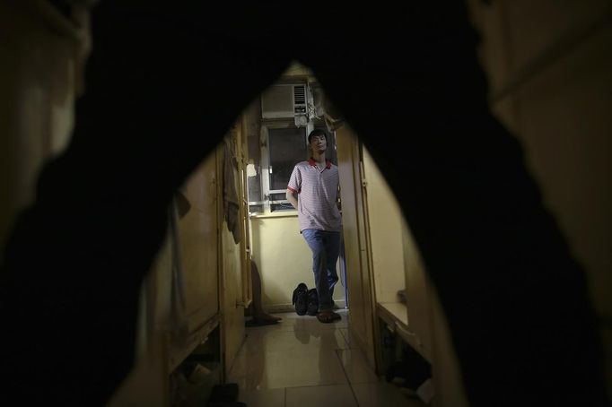 Ah Gut, 40, stands between wooden boxes people use for living in Hong Kong October 9, 2012. In Hong Kong's middle-class residential area, short distance from its shopping and financial districts, 24 people live in these wooden boxes, or "coffin homes", packed in a single apartment of little over 50 square meters. Its residents pay 1450 Hong Kong dollars ($180) for their living space built of wooden panels of 2 meters by 70 cm. To maximize income from the rent in central Hong Kong landlords build "coffin homes", nicknamed due to their resemblance to real coffins. Space has always been at a premium in Hong Kong where developers plant high-rises on every available inch. REUTERS/Damir Sagolj (CHINA - Tags: SOCIETY REAL ESTATE BUSINESS) Published: Říj. 9, 2012, 1:59 odp.