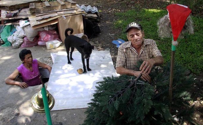 Miguel Restrepo, 62, and wife Maria Garcia (R) make Christmas ornaments outside their sewer home in Medellin December 4, 2012. The former drug addict has been living in an abandoned sewer with his wife and dog Blackie for 22 years. Their home, which is fitted with a kitchen, a fan, tv, a chair and a bed, is a 6 square meter wide and 1.4 meters high tunnel that leaks when it rains, and requires a manhole cover. REUTERS/Albeiro Lopera (COLOMBIA - Tags: SOCIETY POVERTY) Published: Pro. 4, 2012, 9:42 odp.