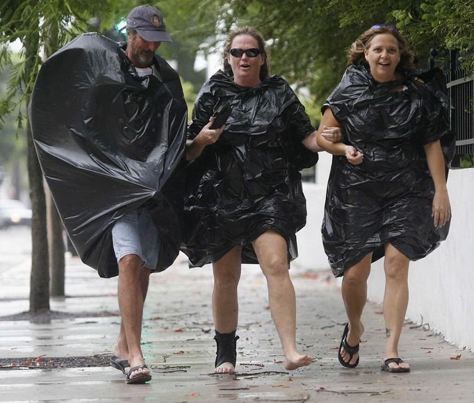 As Tropical Storm Isaac moves over the island, Allen Weeks (L) Julie Beard ( C ) and Sherry Wright make their way home from a bar wearing garbage bags to protect themselves against the rain in Key West, August 26, 2012. Tropical Storm Isaac lashed south Florida with winds and heavy rain on Sunday after battering the Caribbean, disrupting plans for the Republican National Convention in Tampaand threatening to interrupt about half of U.S. offshore oil output. REUTERS/Andrew Innerarity (UNITED STATES - Tags: ENVIRONMENT DISASTER) Published: Srp. 26, 2012, 11:38 odp.