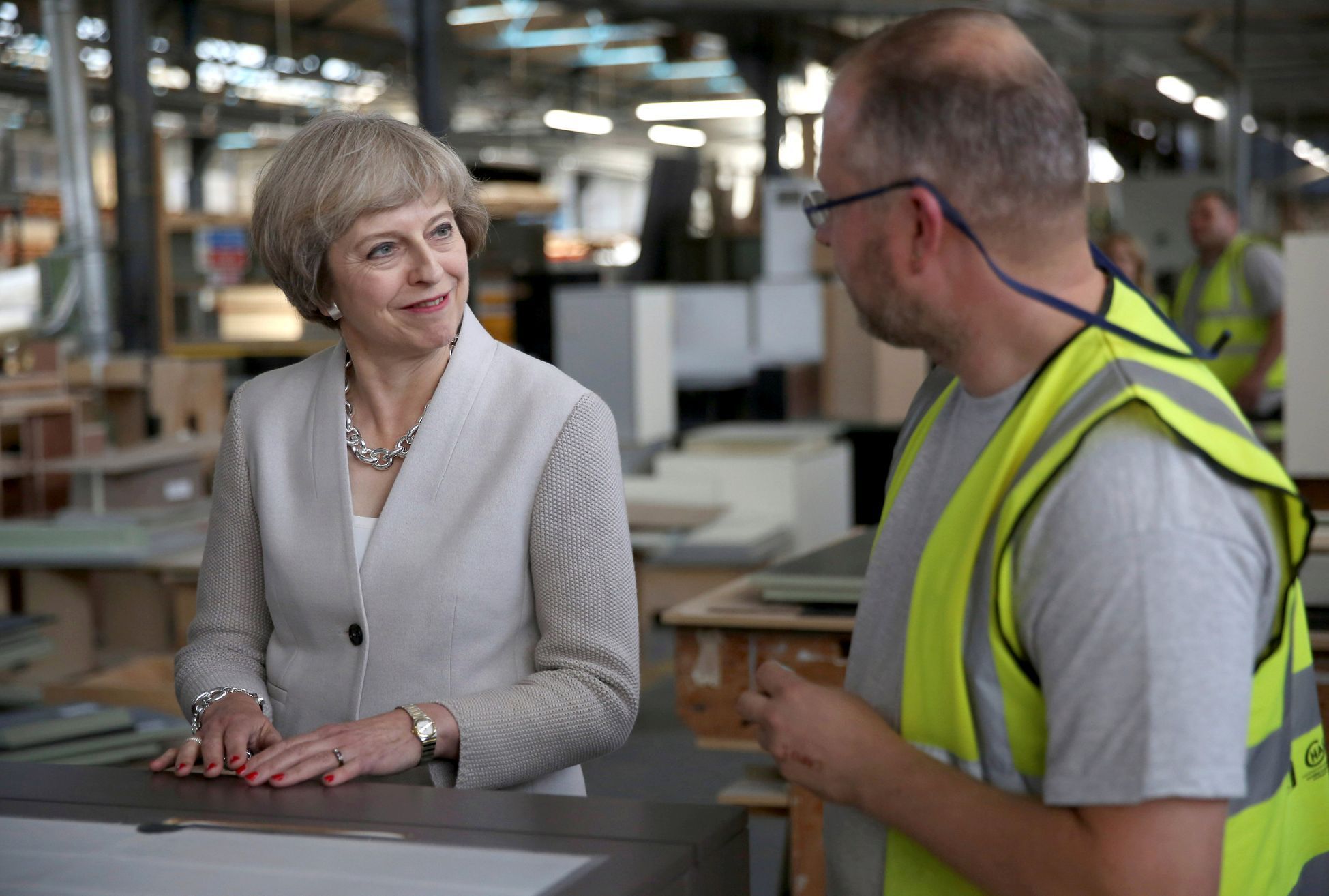 Theresa Mayová hovoří s truhlářem v londýnské továrně.
