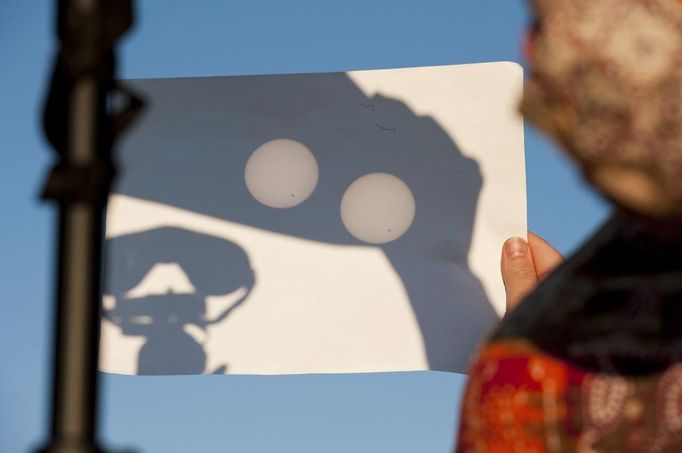 A viewer at Cobbs Hill Reservoir uses binoculars to project the planet Venus (visible as a black dot at lower right of circles) onto a piece of paper as it transits across the sun over Rochester, New York, June 5, 2012. The planet Venus made a slow transit across the face of the sun on Tuesday, the last such passing that will be visible from Earth for 105 years. REUTERS/Adam Fenster (UNITED STATES - Tags: ENVIRONMENT SCIENCE TECHNOLOGY SOCIETY) Published: Čer. 6, 2012, 3:25 dop.