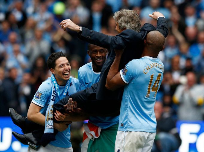 Manchester City's manager Manuel Pellegrini is lifted by his players as they celebrate winning the English Premier League trophy following their soccer match against West