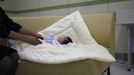 A ward official takes care of a baby who was abandoned in a "baby box" at Joosarang church, before the baby's medical examination at a children's hospital in Seoul September 19, 2012. Pastor Lee Jong-rak of the church, who runs a "baby box" where mothers can leave unwanted infants, has seen a sharp increase in the number of newborns being left there because, the pastor says, of a new law aimed protecting the rights of children. South Korea is trying to shed a reputation of being a source of babies for adoption by people abroad. It is encouraging domestic adoption and tightening up the process of a child's transfer from birth mother to adoptive parents. Picture taken September 19, 2012. REUTERS/Kim Hong-Ji (SOUTH KOREA - Tags: SOCIETY) Published: Říj. 7, 2012, 6:49 dop.