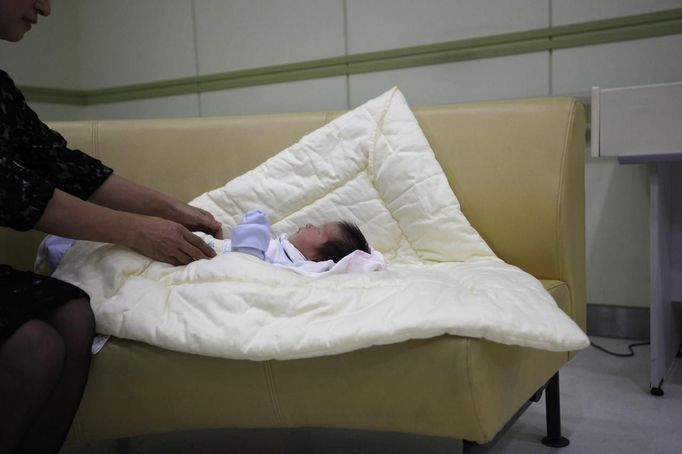 A ward official takes care of a baby who was abandoned in a "baby box" at Joosarang church, before the baby's medical examination at a children's hospital in Seoul September 19, 2012. Pastor Lee Jong-rak of the church, who runs a "baby box" where mothers can leave unwanted infants, has seen a sharp increase in the number of newborns being left there because, the pastor says, of a new law aimed protecting the rights of children. South Korea is trying to shed a reputation of being a source of babies for adoption by people abroad. It is encouraging domestic adoption and tightening up the process of a child's transfer from birth mother to adoptive parents. Picture taken September 19, 2012. REUTERS/Kim Hong-Ji (SOUTH KOREA - Tags: SOCIETY) Published: Říj. 7, 2012, 6:49 dop.