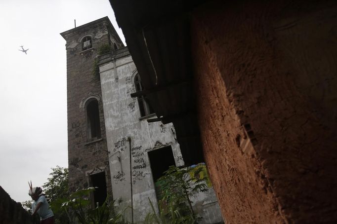 A native Indian looks over the wall at the Brazilian Indian Museum in Rio de Janeiro March 21, 2013. A native Indian community of around 30 individuals have been living in the abandoned Indian Museum since 2006. They have expired a deadline given by a court last Friday to leave the museum within 3 days, local media reported. The group is fighting against the destruction of the museum, which is next to the Maracana Stadium. REUTERS/Ricardo Moraes (BRAZIL - Tags: POLITICS CIVIL UNREST SOCIETY) Published: Bře. 21, 2013, 7:34 odp.