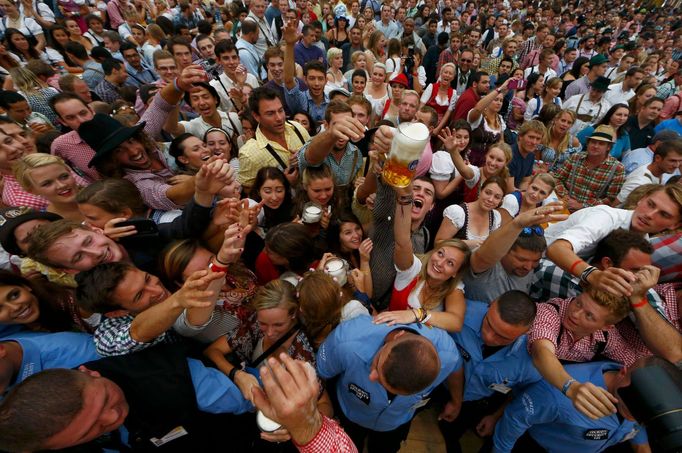 Návštěvníci Oktoberfestu sahající po prvním pivu.