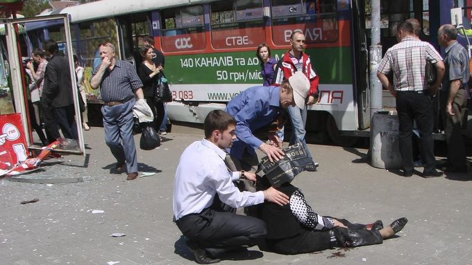 Kolemjdoucí se starají o jednu ze zraněných na tramvajové zastávce