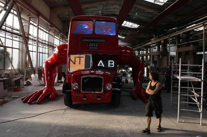 Artist David Cerny walks at a factory hall in Prague as he works on his project to transform a London bus into a robotic sculpture July 2, 2012. The bus, which Cerny hopes could become an unofficial mascot of the London 2012 Olympic Games, does push-ups with the help of an engine powering a pair of robotic arms and the motion is accompanied by a recording of sounds evoking tough physical effort. It will be parked outside the Czech Olympic headquarters in London for the duration of the Games. Picture taken July 2, 2012. REUTERS/Petr Josek (CZECH REPUBLIC - Tags: SOCIETY SPORT OLYMPICS TRANSPORT) Published: Čec. 22, 2012, 5:57 odp.