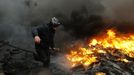 An anti-government protester advances through a burning barricade in Kiev's Independence Square February 20, 2014. Ukrainian protesters hurling petrol bombs and paving st