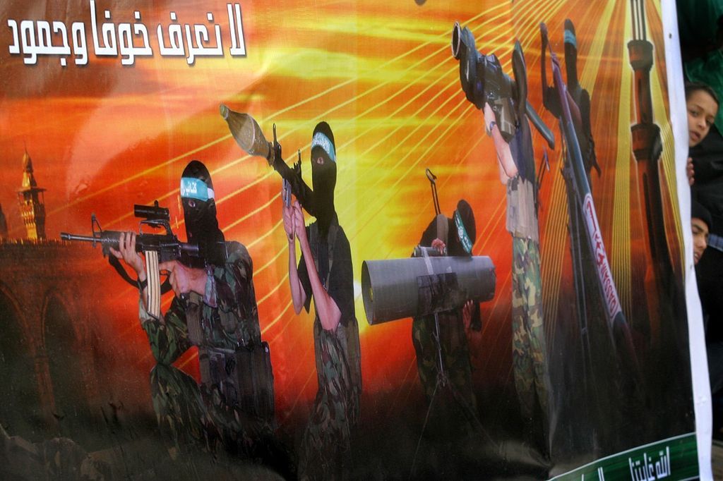 Palestinian children peek from behind a huge banner of Palestinian militants during a rally in support of Hamas movement in the northern Gaza Strip refugee camp of Jabalia 26 November 2004. Jailed West Bank Fatah chief Marwan Barghuti, who has sent word that he wants to run in the Palestinian presidential election, could not carry out his leadership duties from his Israeli cell, legal experts said today.