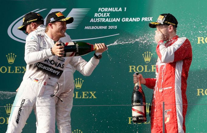 Second placed Mercedes Formula One driver Nico Rosberg of Germany (C) sprays champagne onto the face of third placed compatriot Ferrari driver Sebastian Vettel on the pod