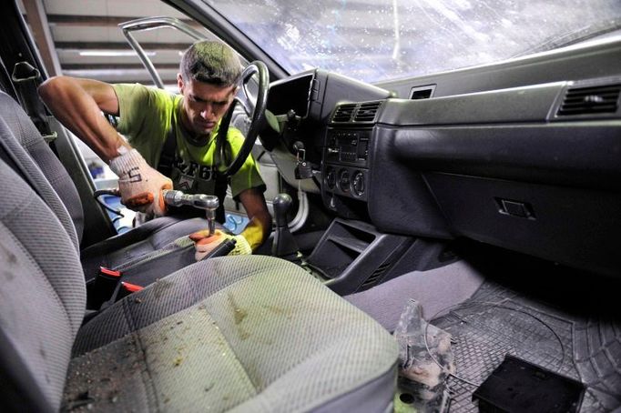 Dělník na slovinském vrakovišti rozebírá auto určené k sešrotování.