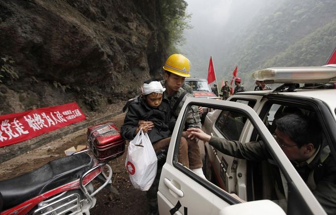 A rescuer carries an injured survivor into a car near a landslide caused by Saturday's earthquake, on a road to Lingguan township, in Baoxing county in Ya'an, Sichuan province April 22, 2013. The 6.6 magnitude quake struck in Lushan county, near the city of Ya'an in the southwestern province of Sichuan, close to where a devastating 7.9 quake hit in May 2008, killing 70,000. The earthquake killed at least 186 people and injured more than 11,000, state media said. REUTERS/Jason Lee (CHINA - Tags: DISASTER ENVIRONMENT) Published: Dub. 22, 2013, 1:22 odp.