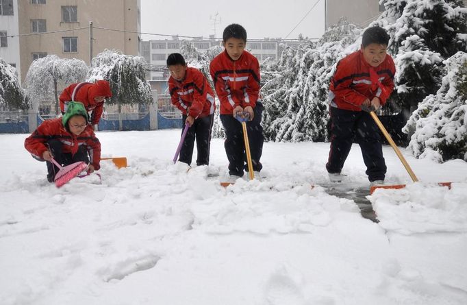 Primary school students shovel snow on their playground after snowfall hit Jilin before winter, in Jilin province October 22, 2012. The cold front sweeping north China will also reach into central and eastern China while bringing snowfall to northeast regions, China's meteorological authorities said here Sunday, Xinhua News Agency reported. REUTERS/China Daily (CHINA - Tags: ENVIRONMENT SOCIETY EDUCATION) CHINA OUT. NO COMMERCIAL OR EDITORIAL SALES IN CHINA Published: Říj. 22, 2012, 8:50 dop.