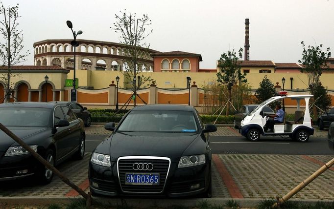 A security guard drives a small vehicle through a carpark outside the surrounding walls of the Florentia Village in the district of Wuqing, located on the outskirts of the city of Tianjin June 13, 2012. The shopping center, which covers an area of some 200,000 square meters, was constructed on a former corn field at an estimated cost of US$220 million and copies old Italian-style architecture with Florentine arcades, a grand canal, bridges, and a building that resembles a Roman Coliseum. REUTERS/David Gray (CHINA - Tags: SOCIETY BUSINESS) Published: Čer. 13, 2012, 5:36 odp.