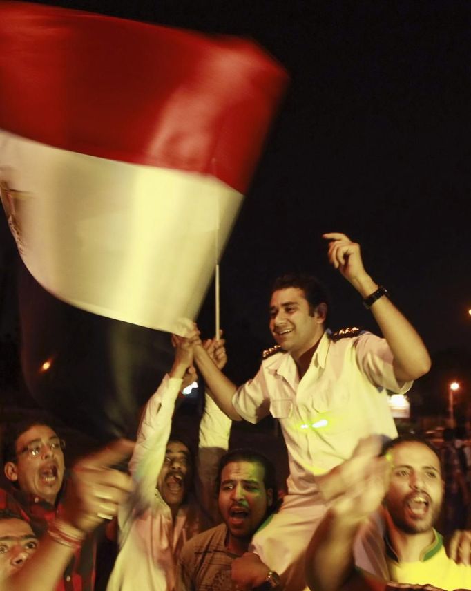 A policeman (C) cheers with protesters, who are against Egyptian President Mohamed Mursi, as they dance and react in front of the Republican Guard headquarters in Cairo July 3, 2013. Egypt's armed forces overthrew elected Islamist President Mohamed Mursi on Wednesday and announced a political transition with the support of a wide range of political, religious and youth leaders. A statement published in Mursi's name on his official Facebook page after head of Egypt's armed forces General Abdel Fattah al-Sisi's speech said the measures announced amounted to "a full military coup" and were "totally rejected". REUTERS/Louafi Larbi (EGYPT - Tags: POLITICS CIVIL UNREST CRIME LAW) Published: Čec. 3, 2013, 8:38 odp.