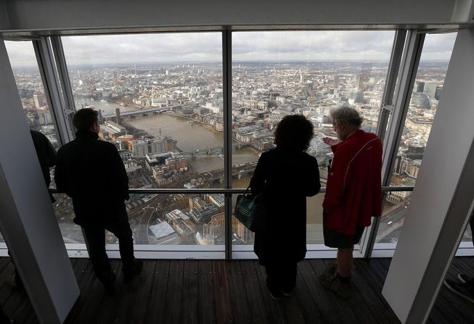 Visitors look out from windows in The View gallery at the Shard in London