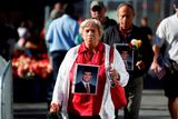 Truchlící přicházejí na Ground Zero před vzpomínkovým ceremoniálem  s fotografiemi těch, kdo zahynuli v troskách Světového obchodního centra.