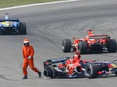 Traťový komisař odchází od havarovaného monopostu Torro Rosso Vitantonia Liuzziho.