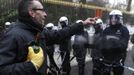 An Arcelor Mittal worker from the Liege site offers whiskey to riot police during a demonstration in Brussels January 25, 2013. ArcelorMittal, the world's largest steel producer, plans to shut a coke plant and six finishing lines at its site in Liege Belgium, affecting 1,300 employees, the group said on Thursday. REUTERS/Eric Vidal (BELGIUM - Tags: BUSINESS CIVIL UNREST EMPLOYMENT) Published: Led. 25, 2013, 3:03 odp.