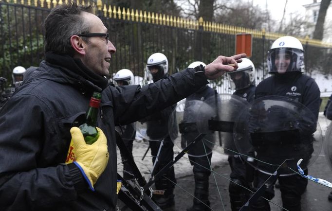 An Arcelor Mittal worker from the Liege site offers whiskey to riot police during a demonstration in Brussels January 25, 2013. ArcelorMittal, the world's largest steel producer, plans to shut a coke plant and six finishing lines at its site in Liege Belgium, affecting 1,300 employees, the group said on Thursday. REUTERS/Eric Vidal (BELGIUM - Tags: BUSINESS CIVIL UNREST EMPLOYMENT) Published: Led. 25, 2013, 3:03 odp.