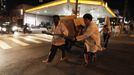 Members of the Traffic Psychologists perform as they help a man to push a cart loaded with cardboard in front of a traffic light in Sao Paulo July 23, 2012. Traffic Psychologists is a non-profit non-governmental organization which aims to humanize traffic and reduce the level of stress caused to drivers. Sao Paulo has more than 7 million vehicles, according to figures from the state transport authority Detran. Picture taken July 23, 2012. REUTERS/Nacho Doce (BRAZIL - Tags: TRANSPORT SOCIETY) Published: Čec. 24, 2012, 7:24 dop.