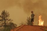 Zoufalý vesničan se snaží zachránit svůj dům před plameny ve vesnici Varvasaina