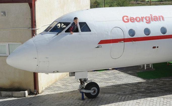 A picture taken on October 29, 2012, shows little boy waiving from a window of a Soviet-era Yakovlev Yak-42 plane turned into their kindergarten in the Georgian city of Rustavi, some 25 km southeast of the capital Tbilisi. Local head teacher Gari Chapidze bought the old but fully functional Yak-42 from Georgian Airways and refurbished its interior with educational equipment, games and toys but left the cockpit instruments intact so they could be used as play tools.