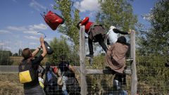Uprchlíci v Maďarsku přelézají ploty.