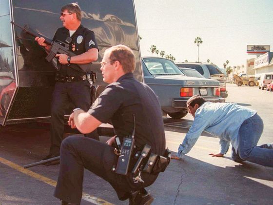 Policejní zásahové složky se kryjí za automobily během přestřelky s bankovními lupiči v Los Angeles v USA. 28. 2. 1997.