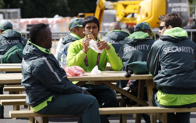 Security guards sit and eat in the London 2012 Olympic Park at Stratford in London July 13, 2012. Security surrounding the Olympics has made the headlines this week after Britain was forced to deploy 3,500 extra troops to fill an embarrassing last-minute shortfall in private security staff.REUTERS/Luke MacGregor (BRITAIN - Tags: SPORT OLYMPICS MILITARY POLITICS) Published: Čec. 13, 2012, 3:05 odp.