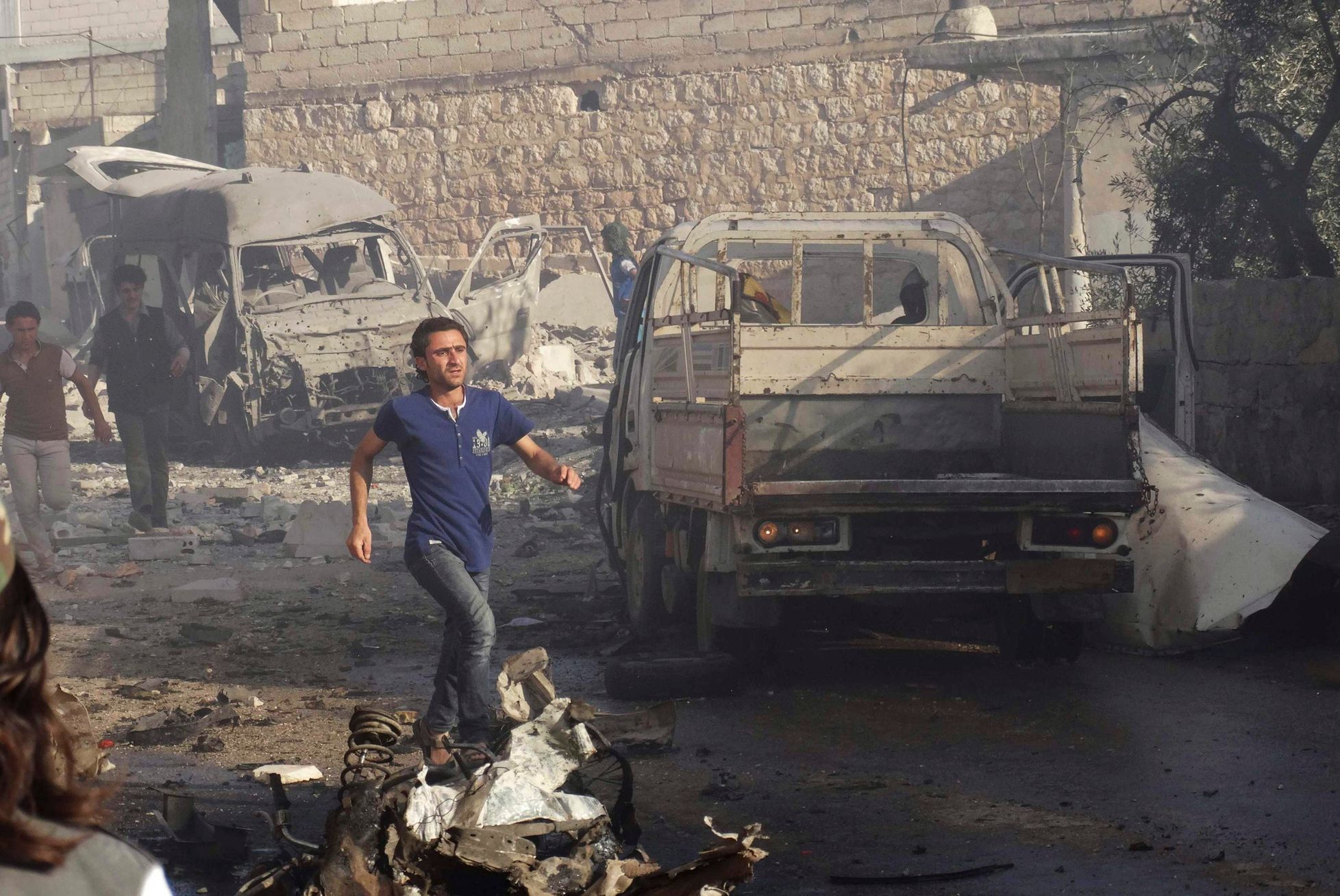 Man runs at a site hit by what activists said were barrel bombs dropped by forces loyal to Syria's President Assad in the northern town of Atareb, in Aleppo province