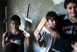 Děti si hrají s vlastnoručně vyrobenými maketami samopalů v jednom ze zničených domů