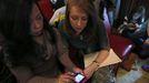 Theresa Volpe (2nd L) and her partner Mercedes Santos (L) look over emails as they wait for the start of an an Illinois Senate Executive Committee hearing on same-sex marriages at the State Legislature in Springfield, Illinois, January 3, 2013. At right is their daughter Ava. Picture taken on January 3, 2013. REUTERS/Jim Young (UNITED STATES - Tags: SOCIETY) Published: Bře. 25, 2013, 6:07 odp.