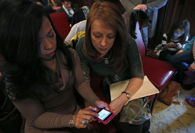 Theresa Volpe (2nd L) and her partner Mercedes Santos (L) look over emails as they wait for the start of an an Illinois Senate Executive Committee hearing on same-sex marriages at the State Legislature in Springfield, Illinois, January 3, 2013. At right is their daughter Ava. Picture taken on January 3, 2013. REUTERS/Jim Young (UNITED STATES - Tags: SOCIETY) Published: Bře. 25, 2013, 6:07 odp.