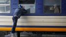 Muž se dívá do okna evakuačního vlaku. Na hlavním nádraží v Kyjevě se loučí se s příbuznými, kteří prchají do Lvova.
