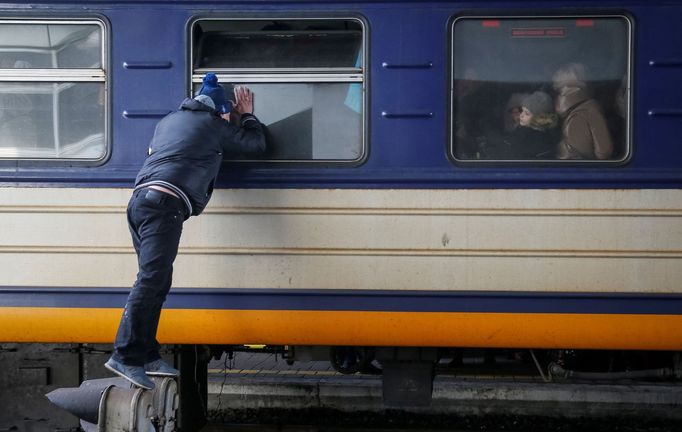 Muž se dívá do okna evakuačního vlaku. Na hlavním nádraží v Kyjevě se loučí se s příbuznými, kteří prchají do Lvova.