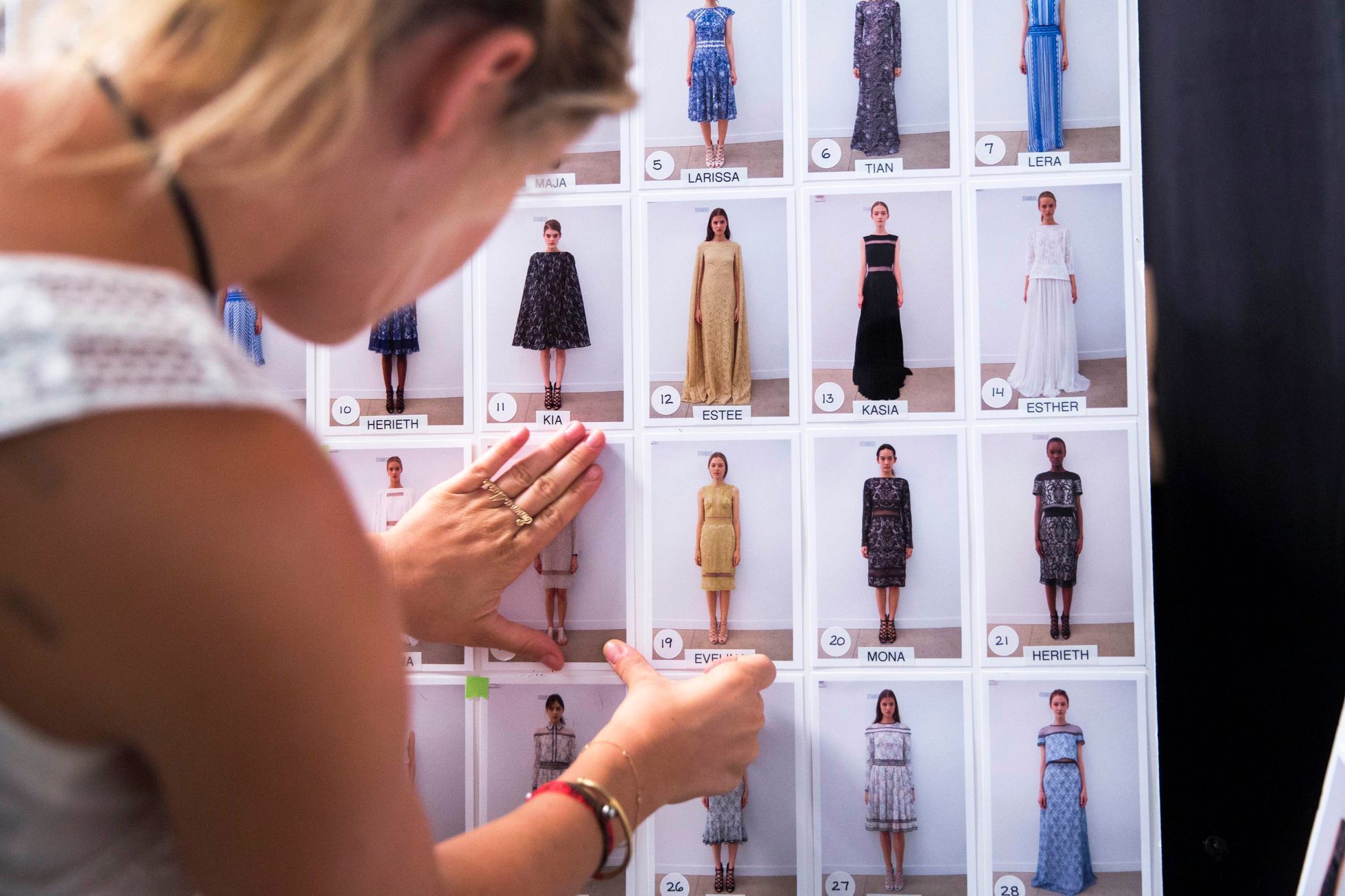 A woman adjusts photographs of models backstage before a showing of the Spring/Summer 2015 Tadashi Shoji collection during New York Fashion Week