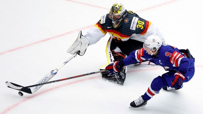 Německý brankář Philipp Grubauer odehrává puk před dotírajícím Američanem Claytonem Kellerem