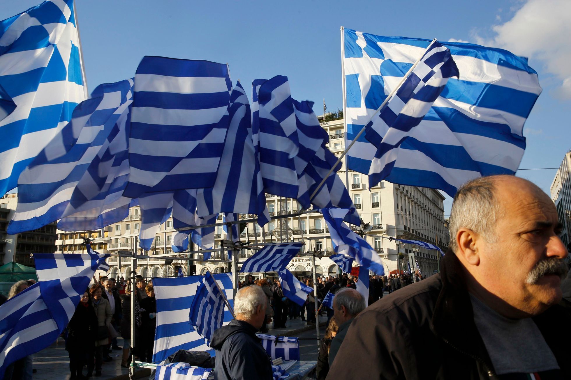Greek national flags displayed for sale flutter during an anti-austerity pro-government demonstration in front of the parliament in Athens